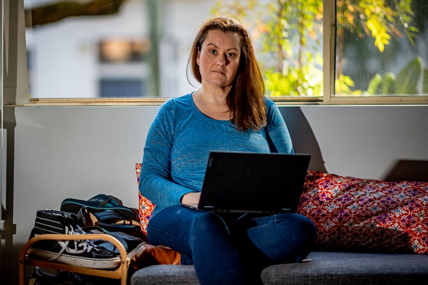 A woman in a blue top with a laptop.
