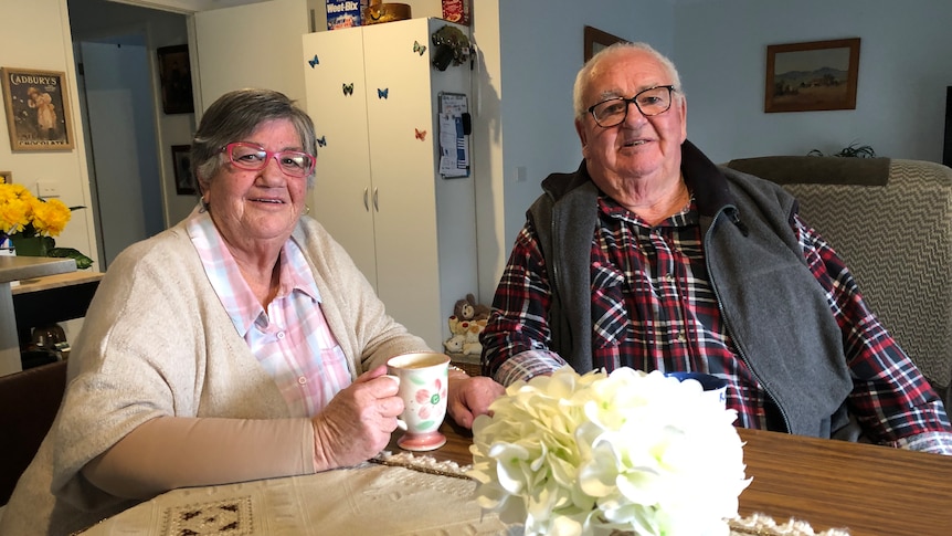 An older couple sitting at the table, having tea.