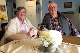 An older couple sitting at the table, having tea.