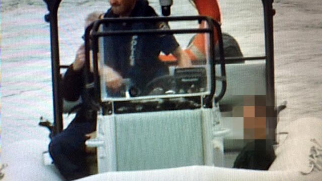 Armed robber Marcus Denis Mayne sits in a police boat after being recaptured and taken into custody.
