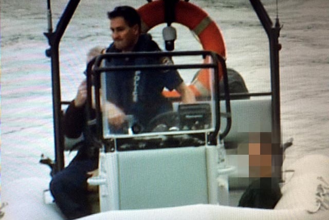 Armed robber Marcus Denis Mayne sits in a police boat after being recaptured and taken into custody.