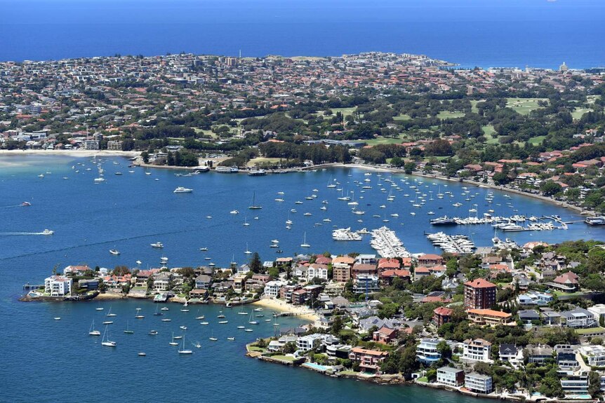 An aerial view shows a big blue ocean and houses in Rose Bay and Point Piper