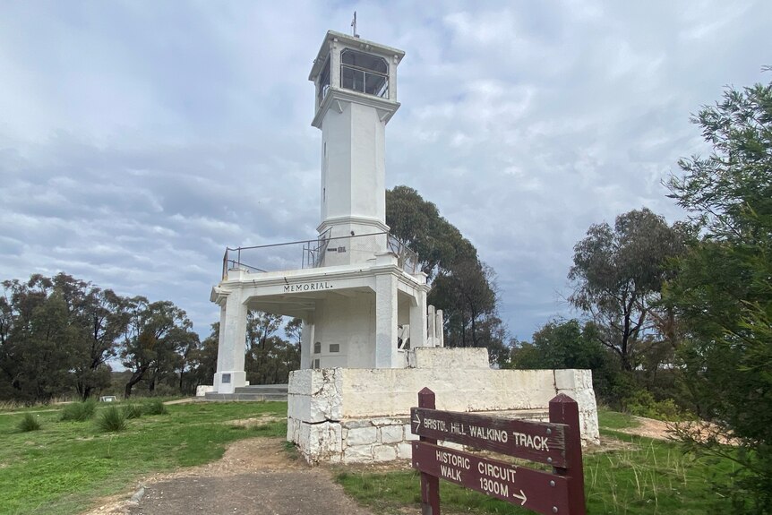 A picture of a white tower lookout on the top of a hill 