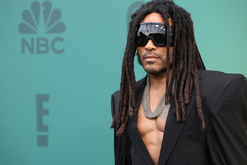 Lenny Kravitz with long locs, dark shades, bare chest and suit jacket