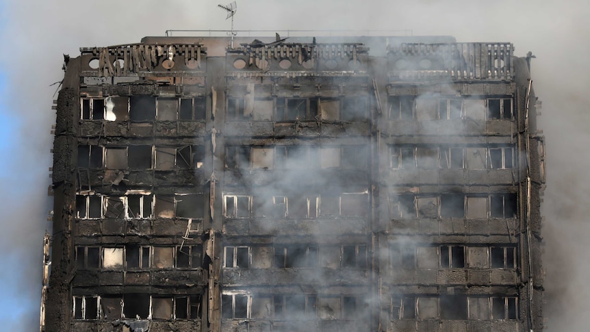 close-up of smoke billows from a tower block severely fire-damaged Grenfell Tower