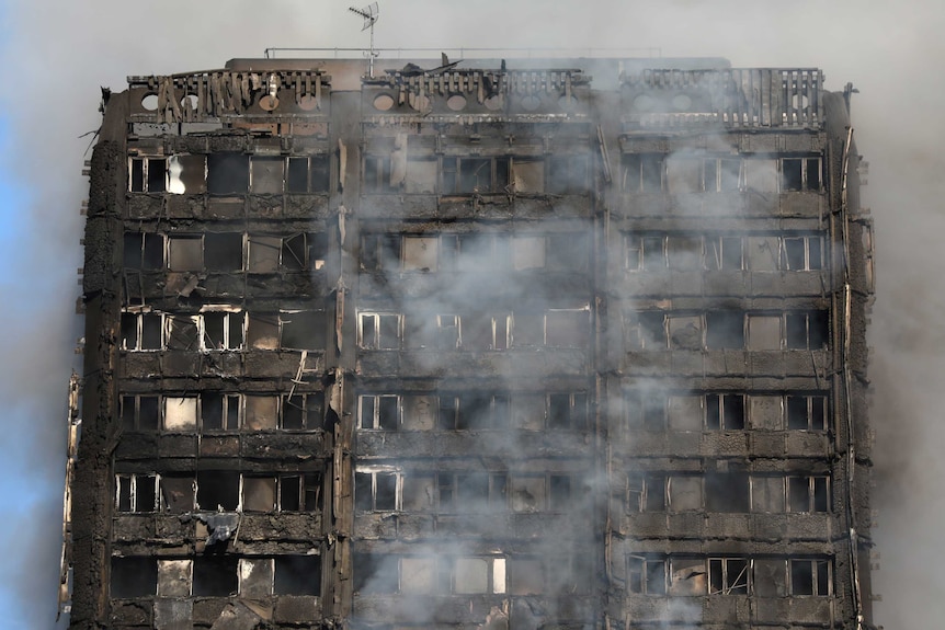 close-up of smoke billows from a tower block severely fire-damaged Grenfell Tower