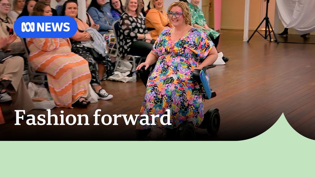 Fashion forward: Woman models bright coloured dress in wheelchair on cat walk. 