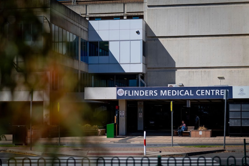 A blue sign with white writing across the front of a hospital building says Flinders Medical Centre
