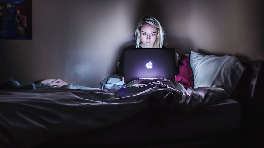 Woman sitting in bed at night with laptop
