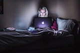 Woman sitting in bed at night with laptop