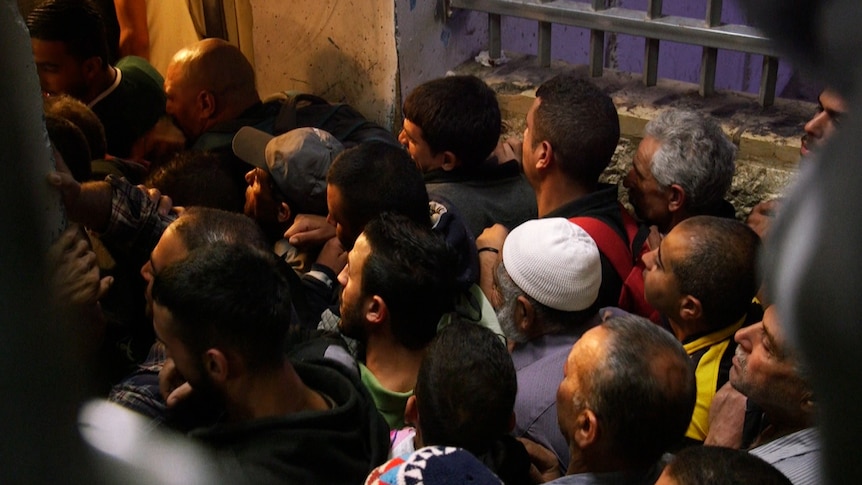 A crowd of men crushes into a doorway at checkpoint 300 in Bethlehem.