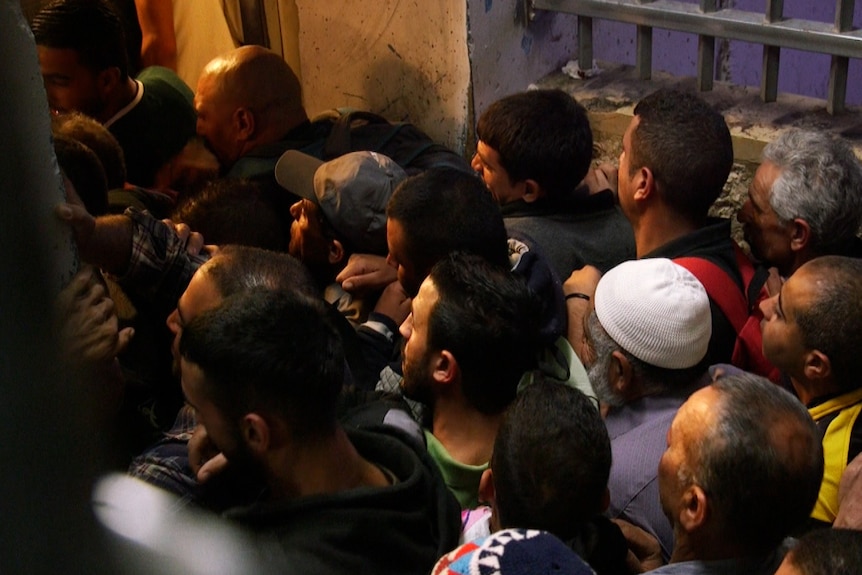 A crowd of men crushes into a doorway at checkpoint 300 in Bethlehem.