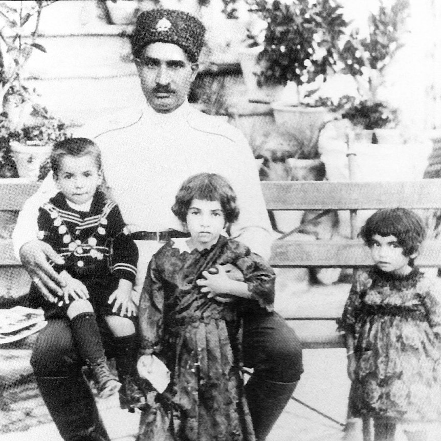 Black and white photo of man with two children on his knees and a third to the side.