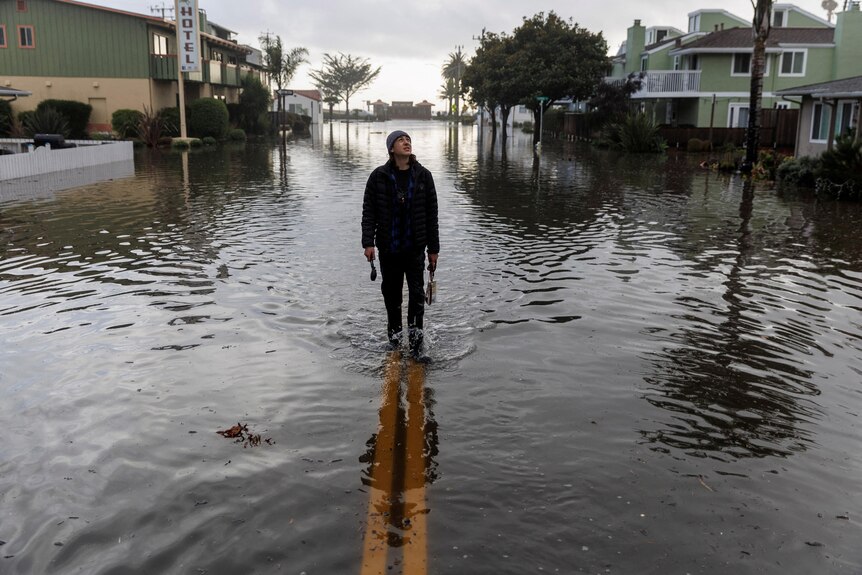 A resident walks along a flooded street in Aptos, California.
