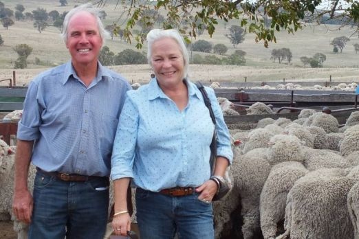 Andrew and Anne Basnett stand by a flock of sheep.