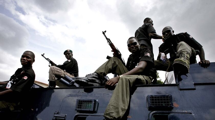 Nigerian police sit atop an armoured personnel carrier