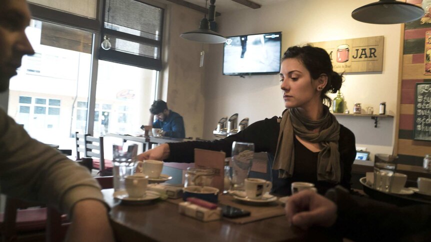 University graduate Vanja serves customers at a cafe.