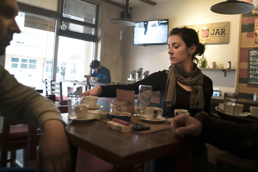 University graduate Vanja serves customers at a cafe.
