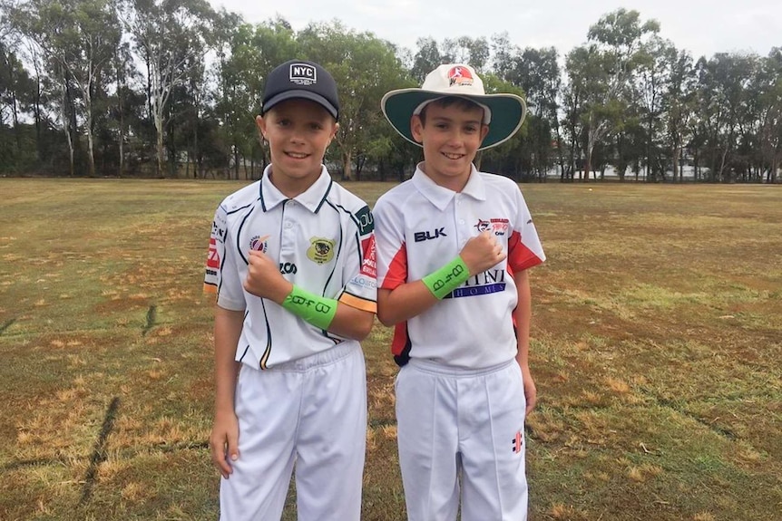 Two young boys in cricket gear.