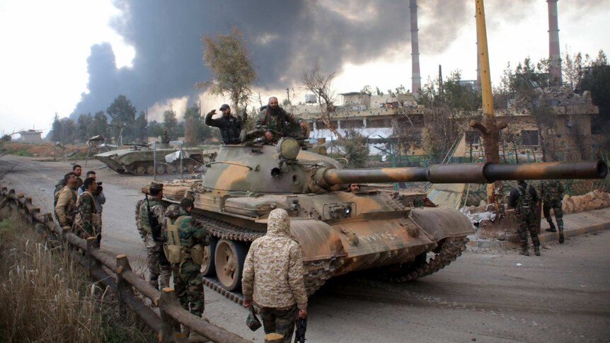 Syrian government forces patrol with a tank.