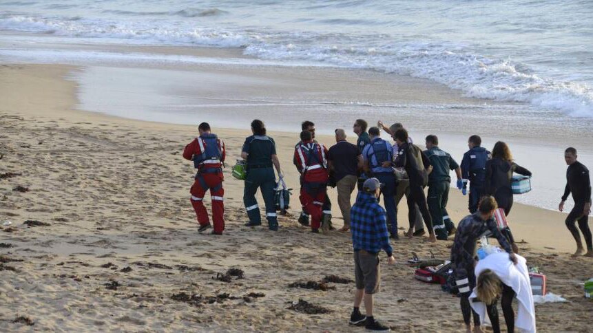 A surfer injured in a shark attack is carried from the beach on a stretcher by rescuers.