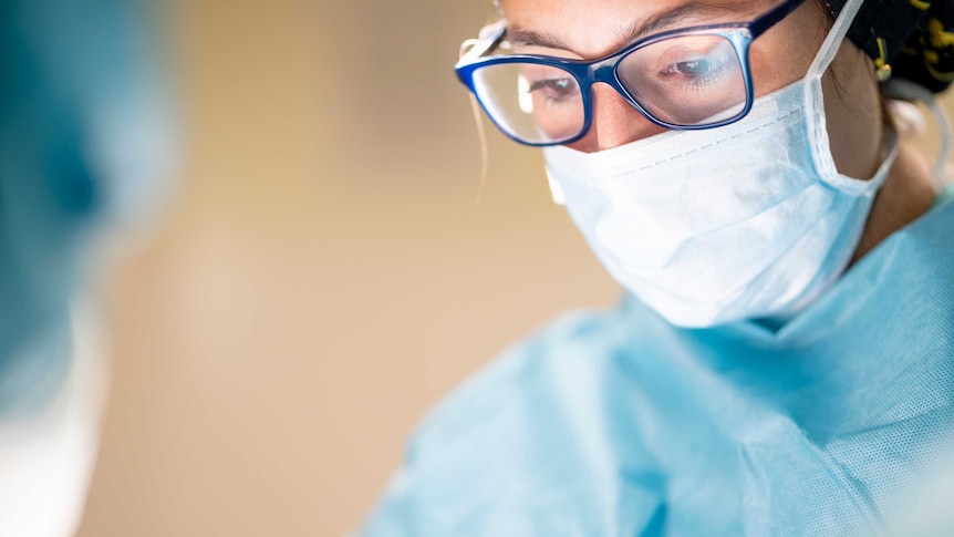 Female surgeon wears mask during operation.