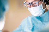 Female surgeon wears mask during operation.