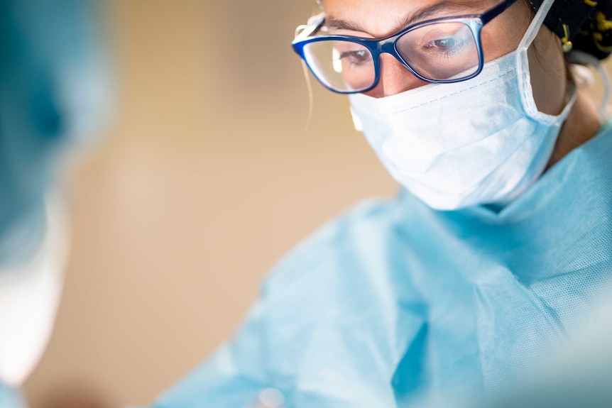 Female surgeon wears mask during operation.