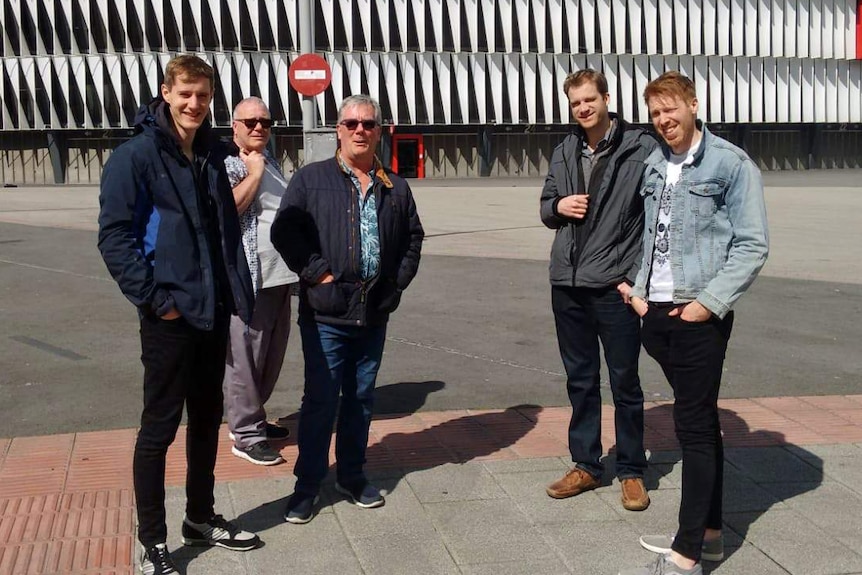 Alan Dennison stands outside with four other men.