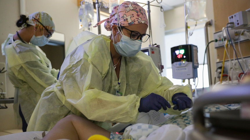 A critical care nurse, administers an anti-viral medication to a COVID-19 positive patient.