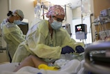 A critical care nurse, administers an anti-viral medication to a COVID-19 positive patient.