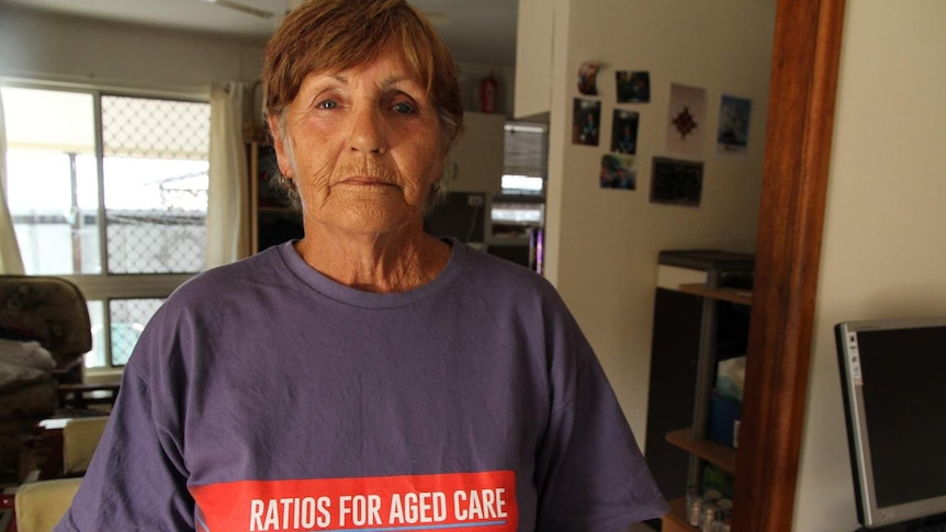A woman wearing a purple shirt with red writing that says 'ratios for aged care' stands front on looking at the camera