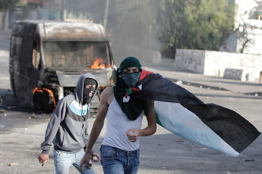 Masked Palestinian youths hold rocks during clashes with Israeli security forces in east Jerusalem.