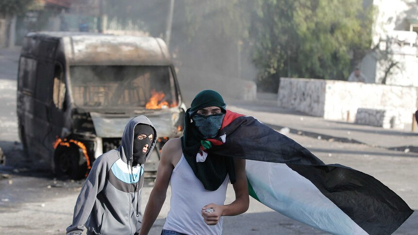 Masked Palestinian youths hold rocks during clashes with Israeli security forces in east Jerusalem.