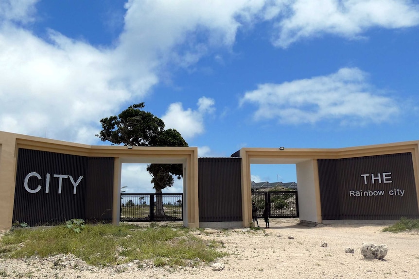 The front gates of Rainbow City. They are big and brown with the words "CITY" and "THE Rainbow city" on the left and right sides