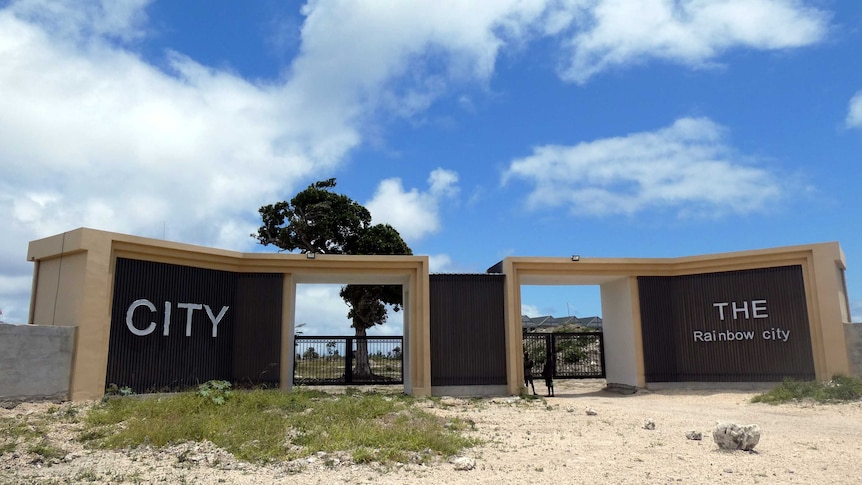 The front gates of Rainbow City. They are big and brown with the words "CITY" and "THE Rainbow city" on the left and right sides