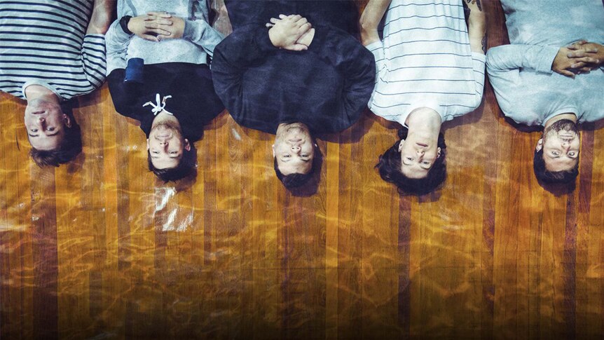 Press shot of the band Trophy Eyes on a yellow background. The band are upside down. It's a picture from the year 2016.