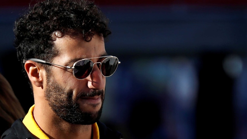 Daniel Ricciardo wears round sunglasses with a neutral expression