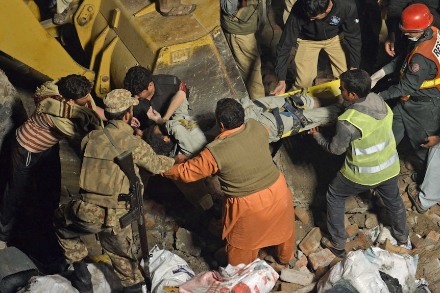 Rescuers move a victim through the rubble of the collapsed factory.