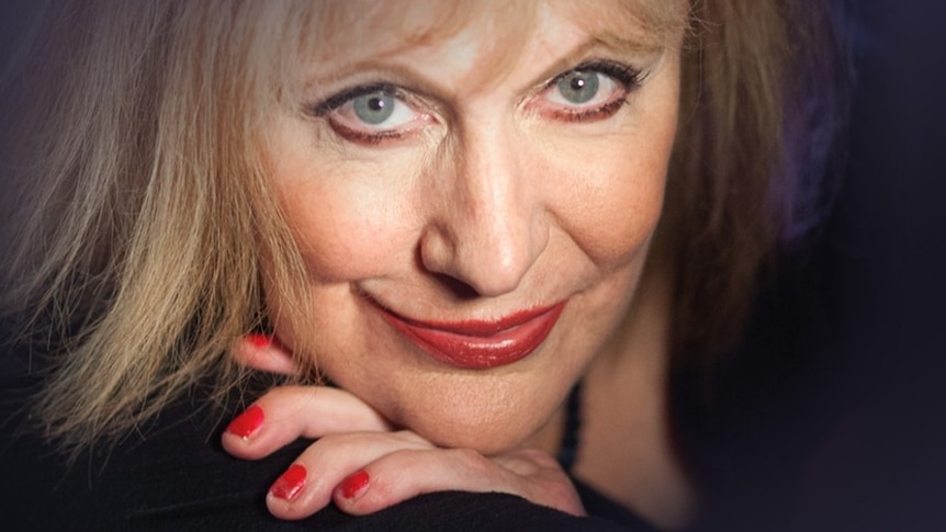A closeup of Australian soul artist Renee Geyer. She has her hand under her chin and a red-lipped slight smile.