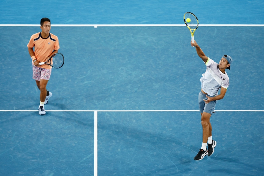 Jason Kubler smashes as doubles partner Rinky Hijikata looks on