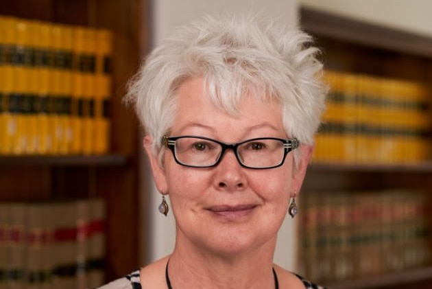 A head shot of a lady pictured in front of a book case