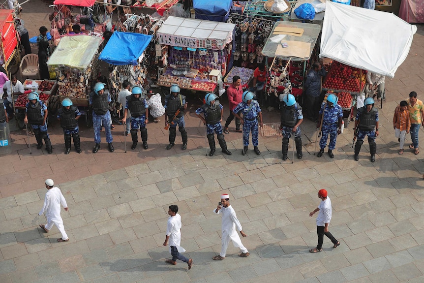 Indian Muslims walk in a line past security in Hyderabad