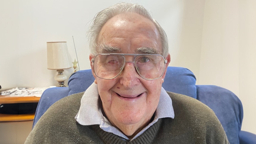 A close up of an elderley man wearing glasses and a big smile.
