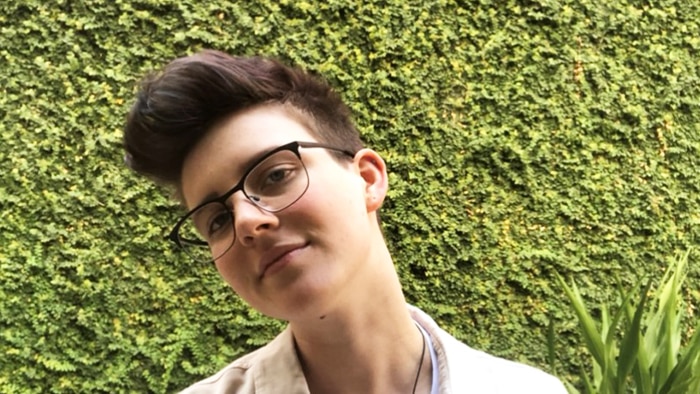 Melbourne University student Charlie Laverty standing in front of a hedge.