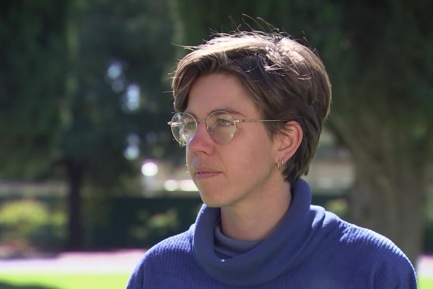 woman with brown crop hair wearing glasses and blue tunic