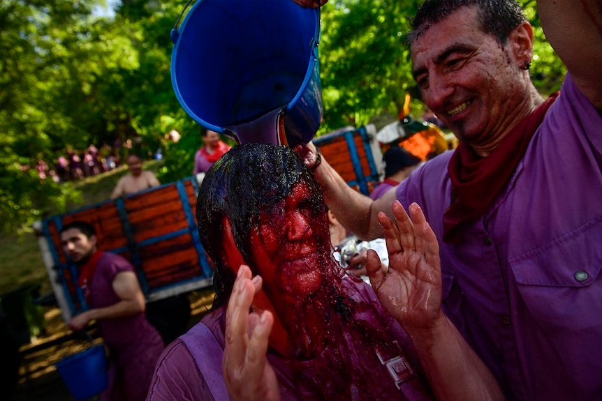 A reveller is covered in wine as people take part in a wine battle.