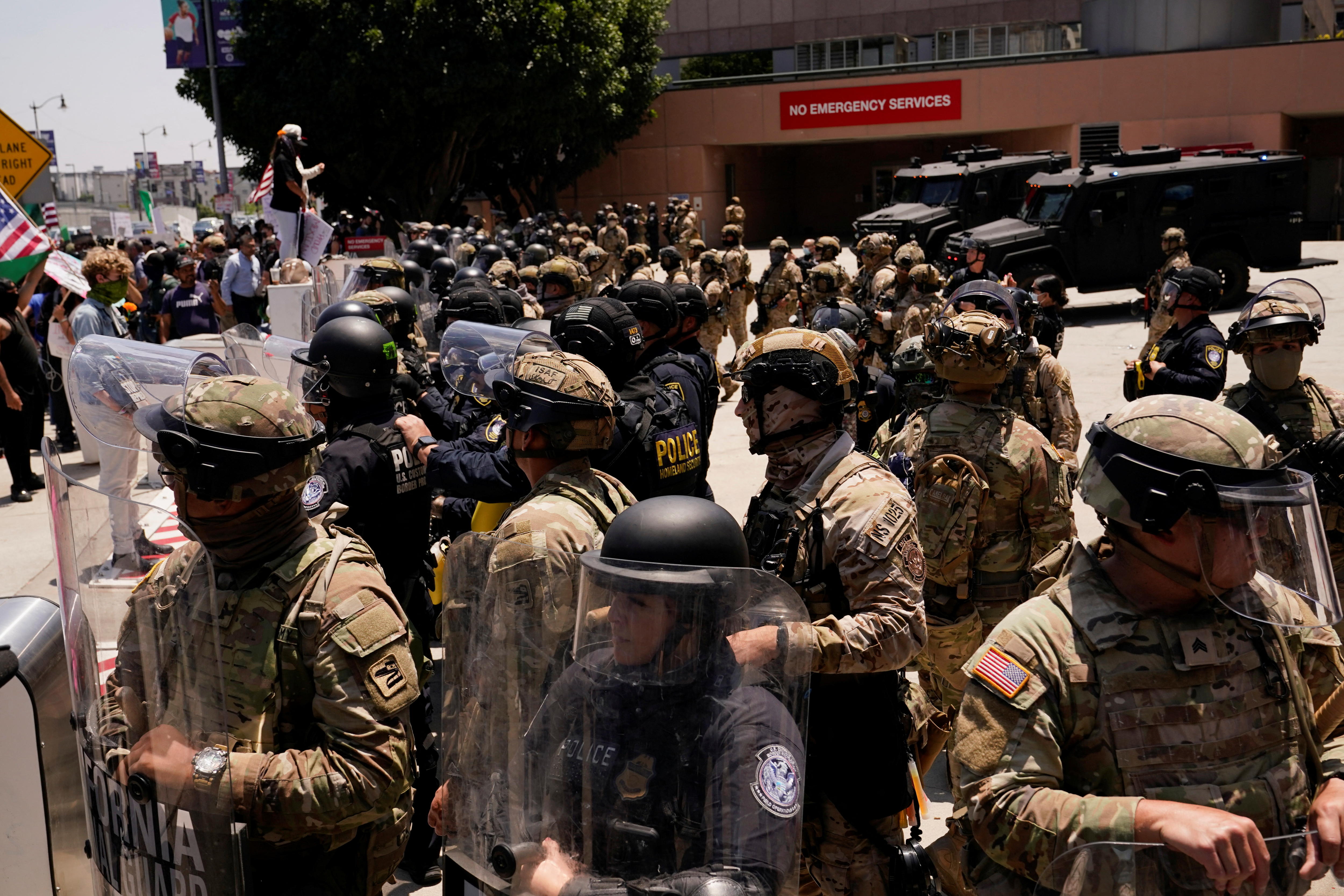 Dozens of troops in camouflage fatigues stand as a barricade in front of protesters.