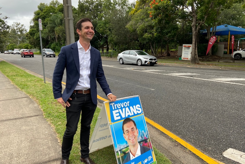 A man smiling by his election placard.