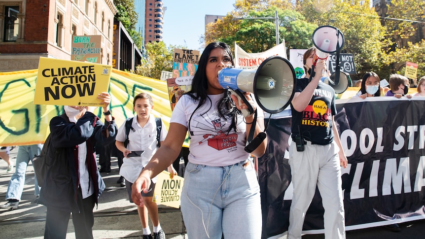 A group of young people march down the street holding banners calling for climate action. 